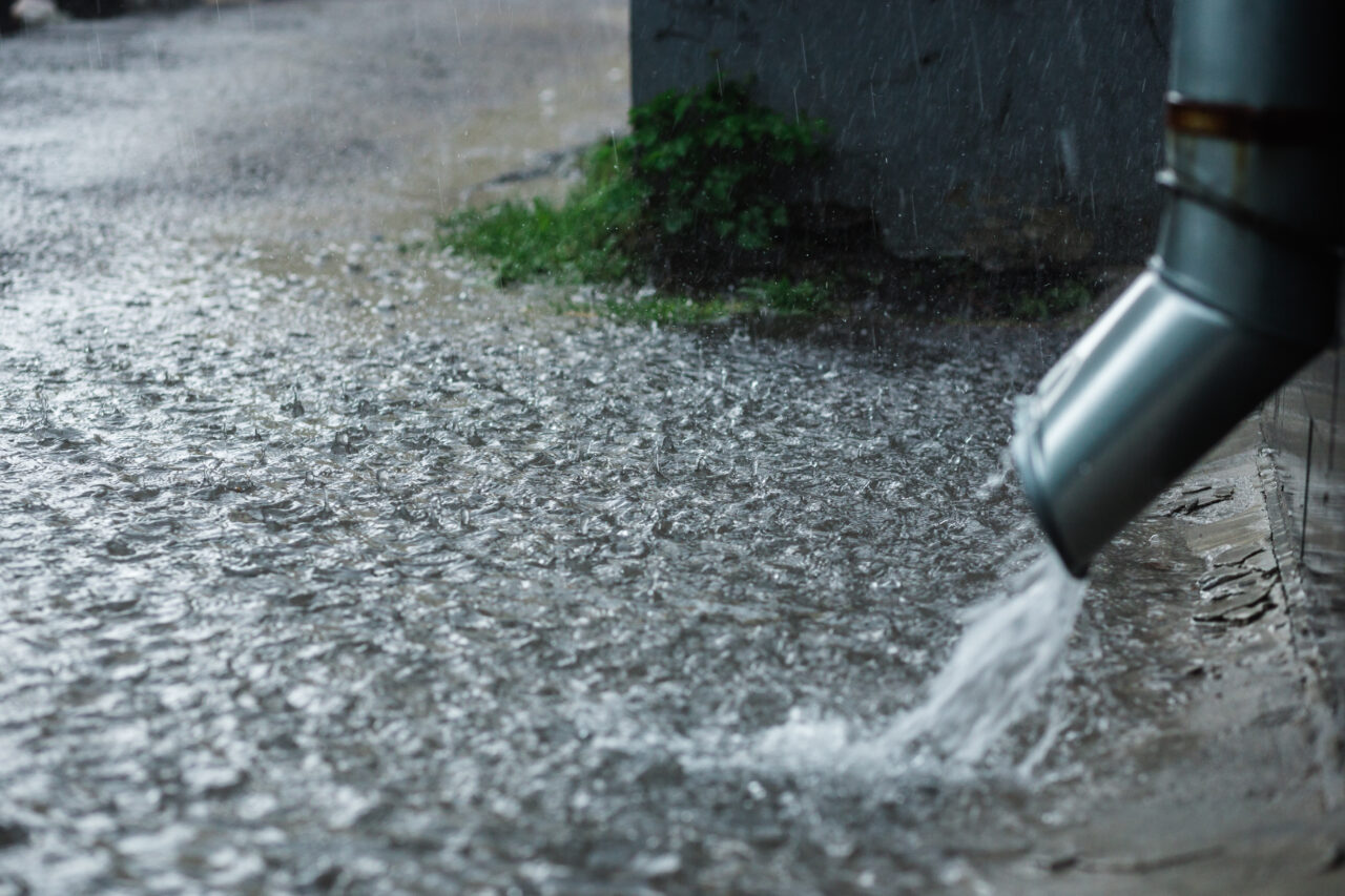 Regenwasser läuft aus einem Fallrohr.